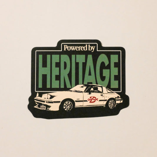 Sticker with 'Powered by Heritage' text and a car illustration on a beige background