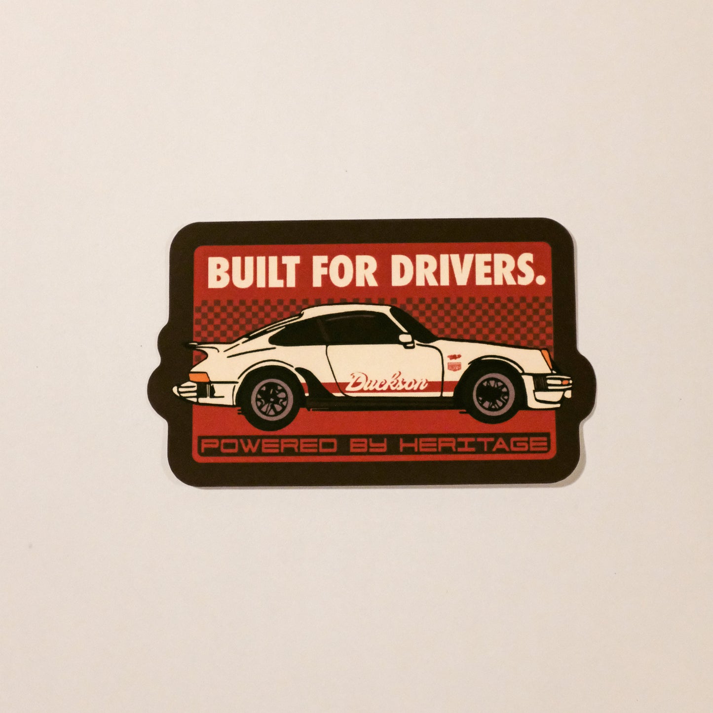 Sticker with a car design and text 'Built for Drivers' on a beige background