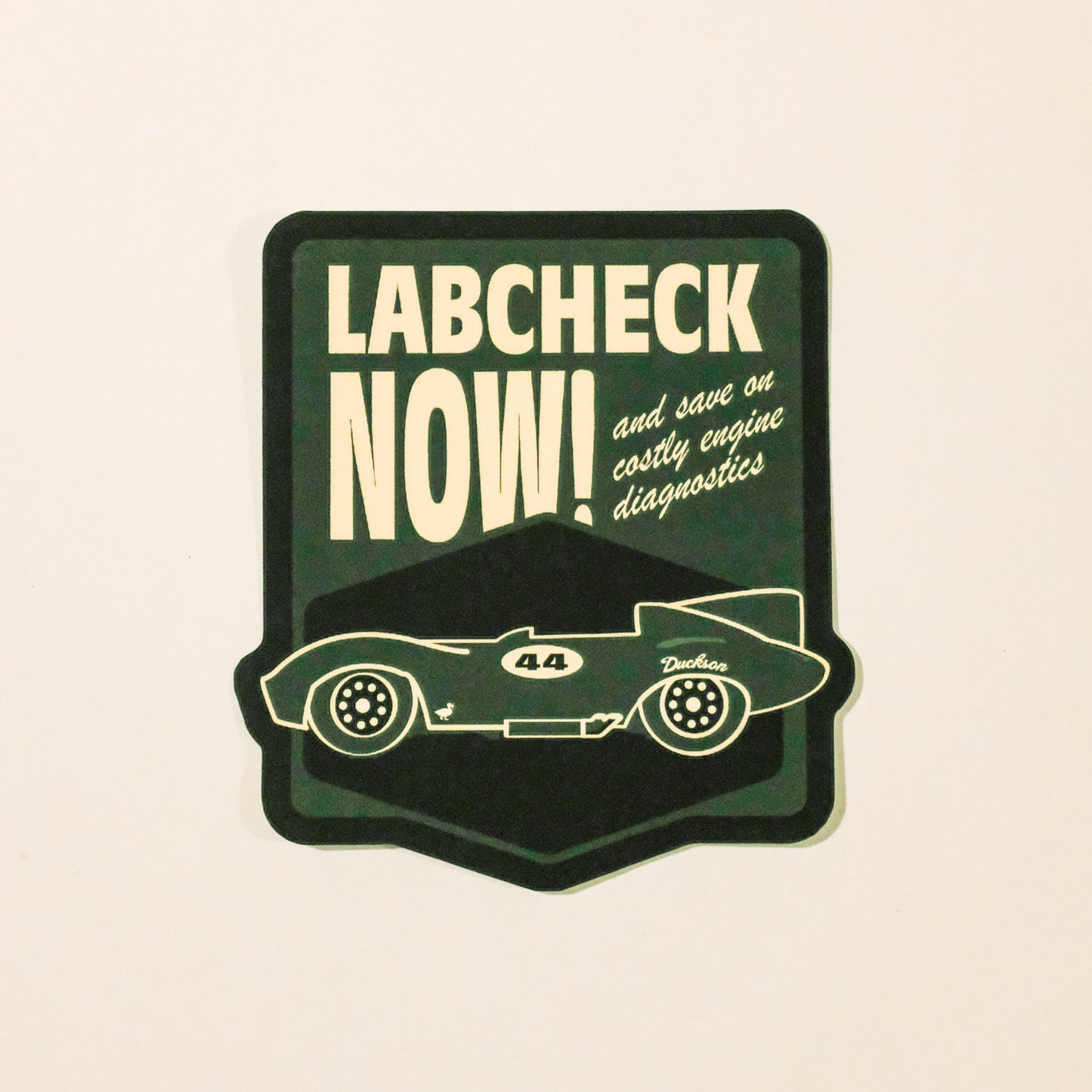 Sticker with a vintage car design and 'Labcheck Now!' text on a beige background