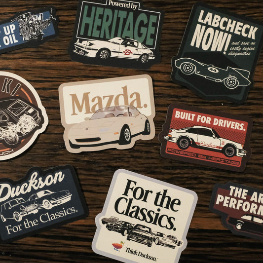 Collection of automotive-themed stickers on a wooden surface